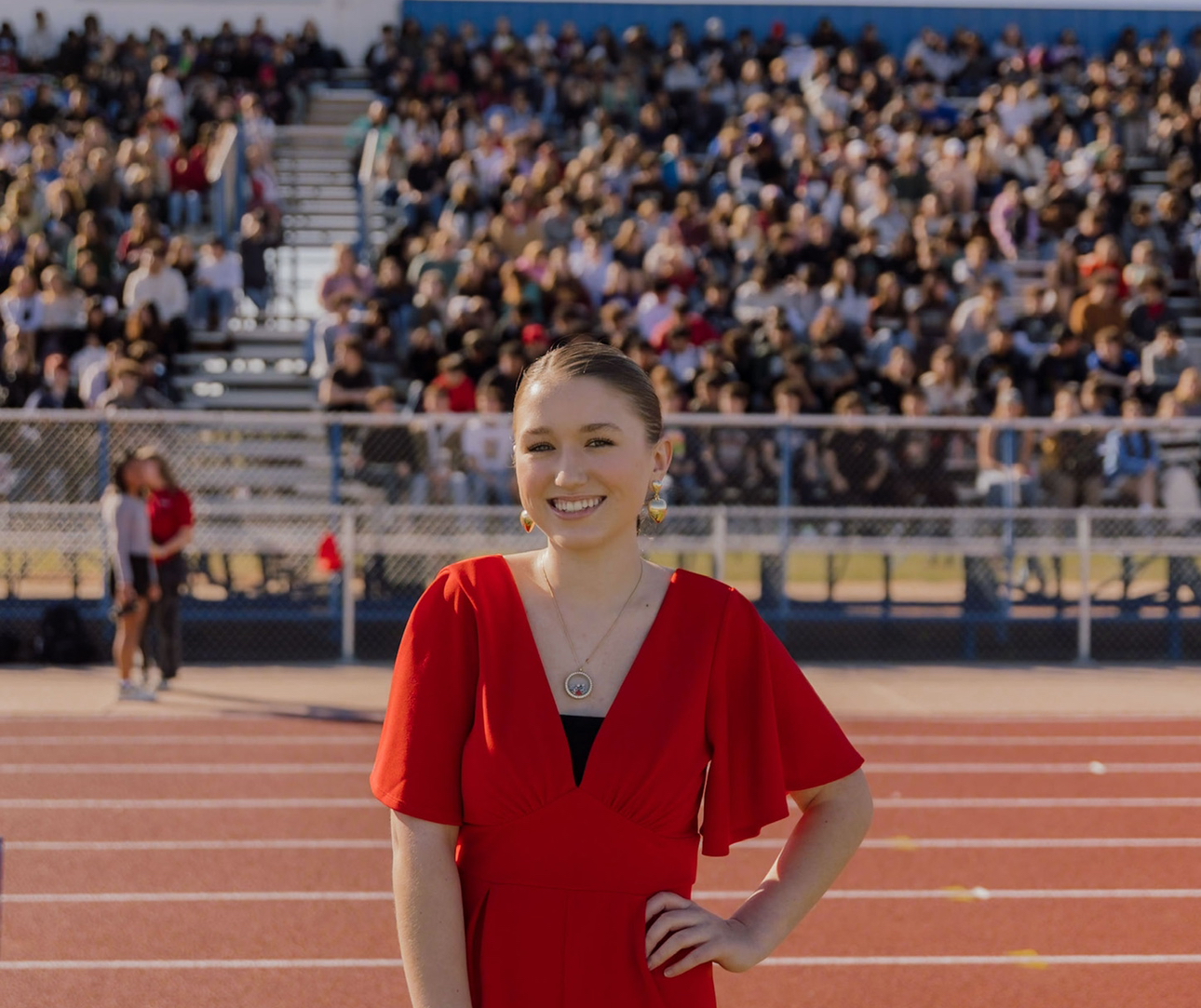 Rosevelt smiling on a track in front of packed bleachers of students