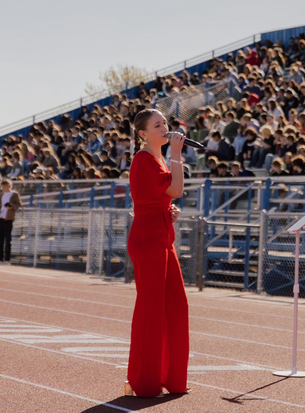 Rosevelt singing in a red jumpsuit in front of packed stadium bleachers