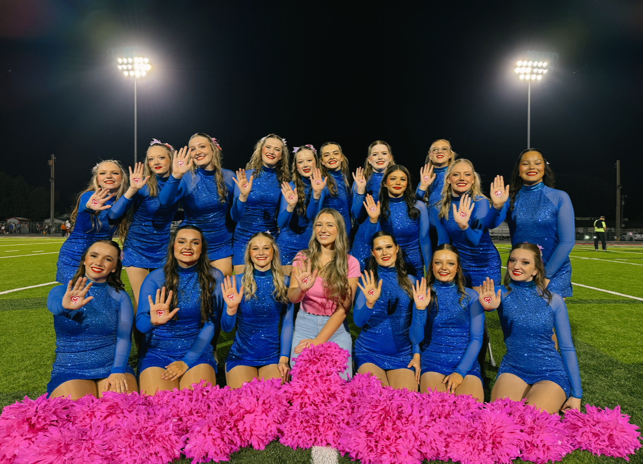 A high school dance team raising hands painted with hearts in support